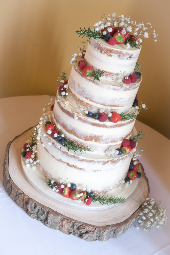 semi naked wedding cake with flowers and berries