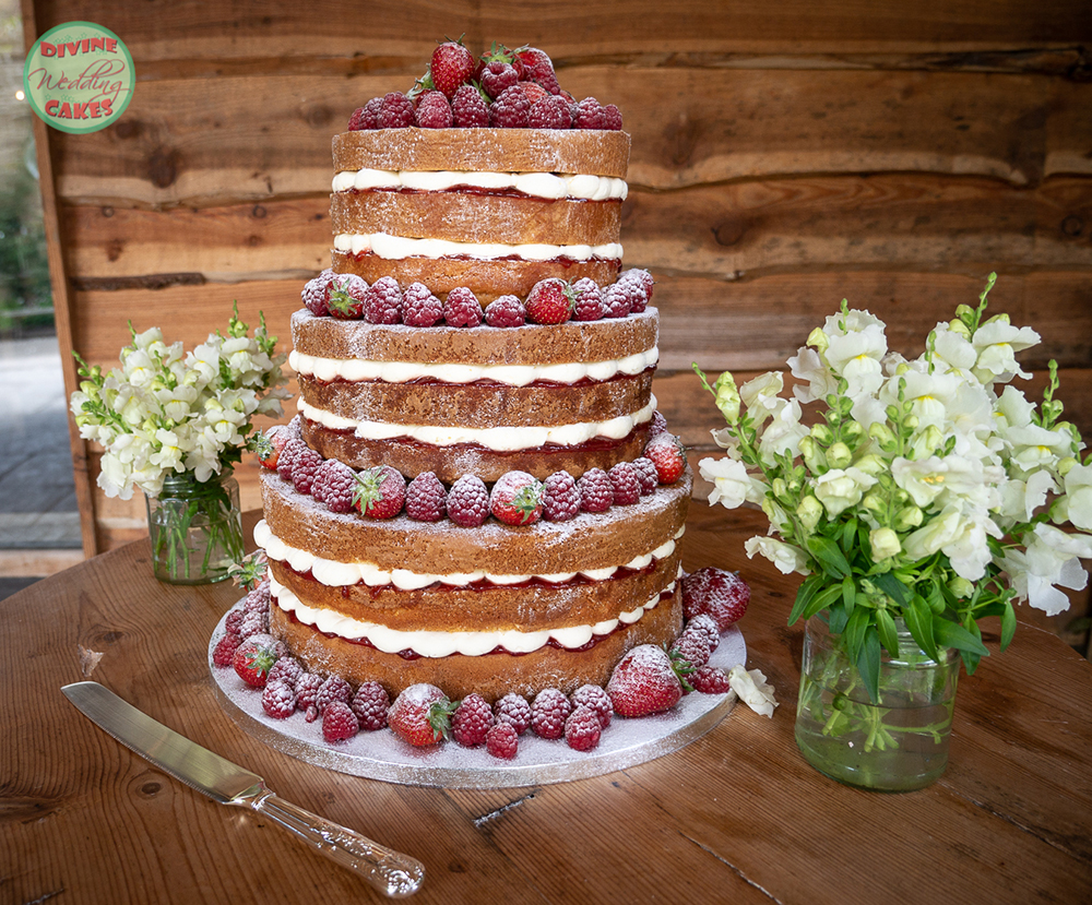a naked wedding cake with strawberries and raspberries