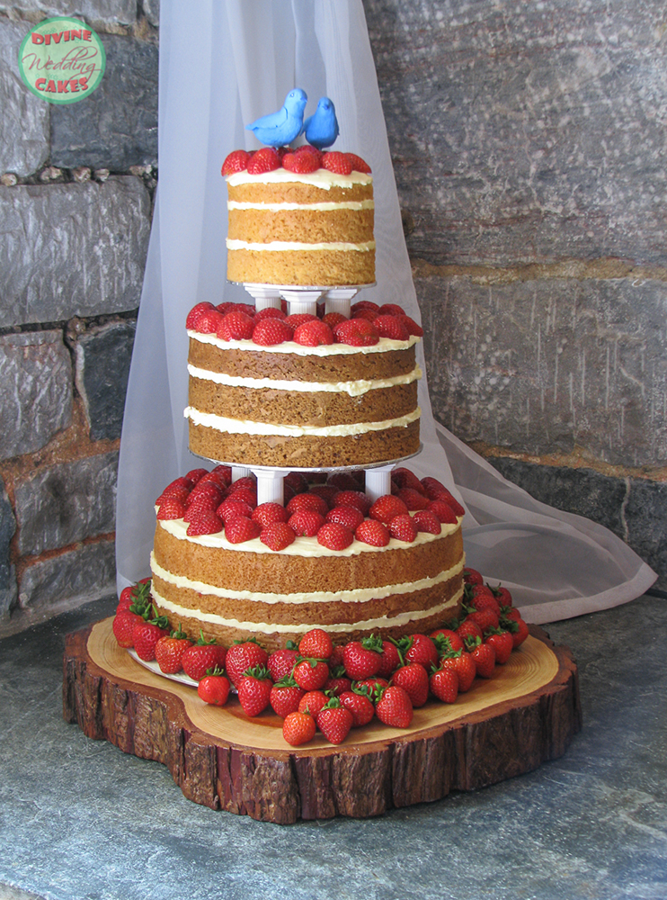 a naked wedding cake covered with strawberries