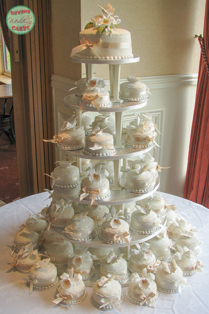 a tower of mini wedding cakes with sugar flowers on top