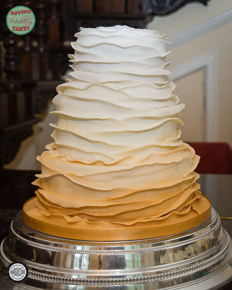 a wedding cake with ruffles and a golden Ombre colour