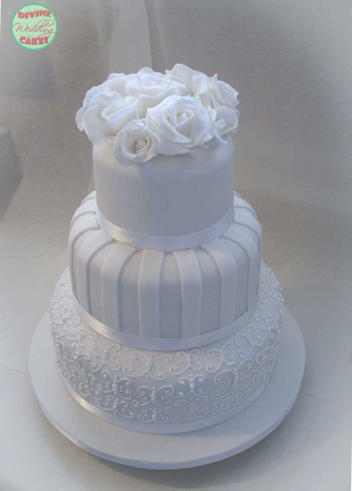 a white fondant iced cake with sugar roses