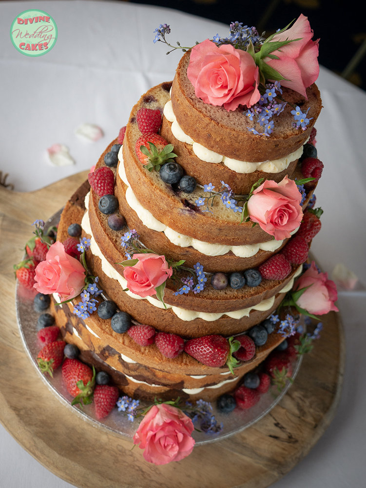 a naked cake with fresh roses, forget-me-nots and summer berries